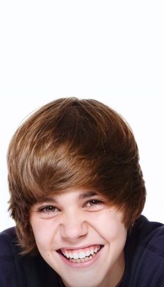 a young boy with brown hair smiling at the camera