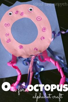 an octopus made out of paper on top of a piece of blue paper with pink and purple ribbons