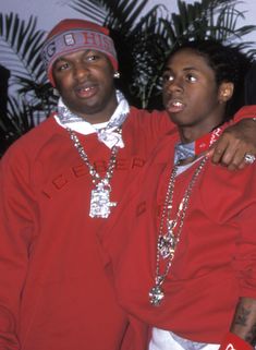 two men standing next to each other wearing red sweatshirts and silver chains on their necks