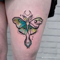 a colorful butterfly tattoo on the thigh