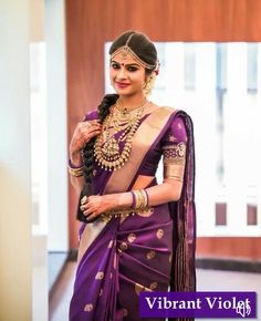 a woman wearing a purple sari and gold jewelry