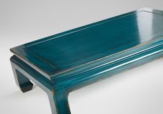 a teal colored wooden bench sitting on top of a white floor