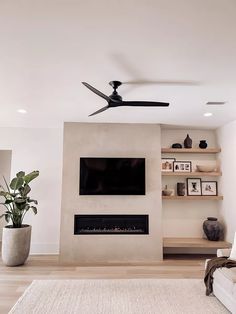 a living room with a ceiling fan and a flat screen tv mounted on the wall