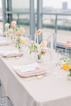 a long table is set with flowers and place settings for the guests to sit at