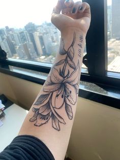 a woman's arm with a flower tattoo on it, in front of a window