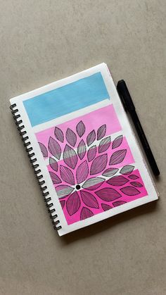 a notebook with a flower drawn on it next to a black pen and paper clip