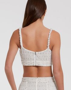 the back of a woman wearing a white crop top and high waist shorts with pearls