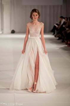 a woman is walking down the runway in a white dress