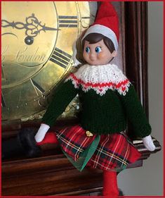 an elf doll is posed next to a clock