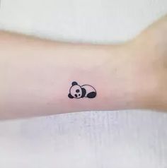 a small panda bear tattoo on the wrist