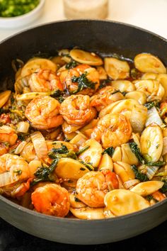 shrimp and spinach stir fry in a skillet on top of a stovetop