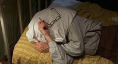 an older man laying in bed with his head on the pillow