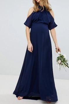 a pregnant woman in a blue dress holding a flower bouquet and posing for the camera