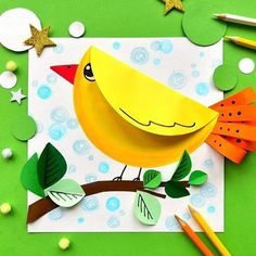 a yellow bird sitting on top of a green table next to pencils and paper