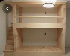 an empty room with some stairs and a light on the ceiling above it, in front of a white wall