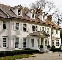 a large white house with lots of windows on the front and side of it's roof