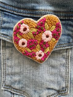 a close up of a heart shaped brooch in the back pocket of someone's jeans