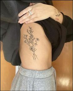 a woman's lower back tattoo with flowers on her ribs and the bottom part of her stomach