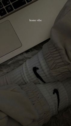 someone's feet in white socks with the word home vibe written on them next to a laptop