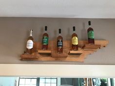 five bottles of liquor are lined up on a wooden shelf in front of a mirror