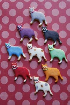 there are many different colored cats on this pink tablecloth with white polka dots in the background