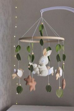 a baby crib mobile with stuffed animals hanging from it's sides and green leaves