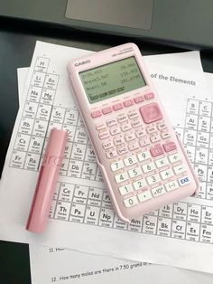 a pink calculator sitting on top of a table next to a pen and paper