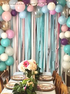 the table is set with plates, flowers and balloons