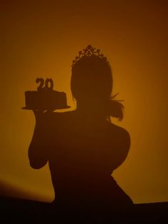 the silhouette of a woman holding a cake