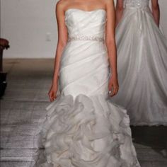 a woman in a white wedding dress walking down the runway