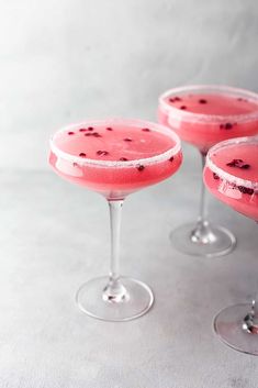 three glasses filled with watermelon and blackberries on top of a white table