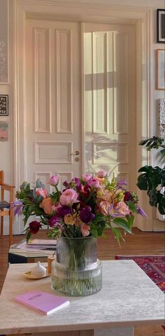 a vase filled with lots of flowers on top of a table next to a door