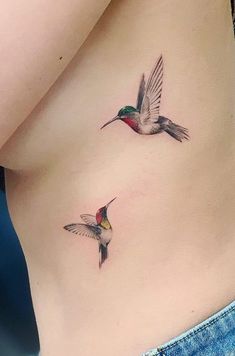 two hummingbirds flying next to each other on the side of a woman's stomach