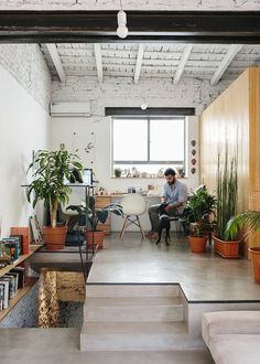 a man sitting at a desk in an office with potted plants on the stairs