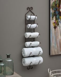 a towel rack with four white towels hanging from it's sides and three metal hooks on the wall