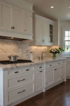 a large kitchen with white cabinets and marble counter tops is pictured in this image from the front view