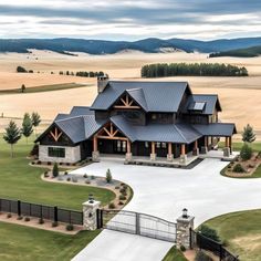 an aerial view of a large home in the middle of a field with mountains behind it