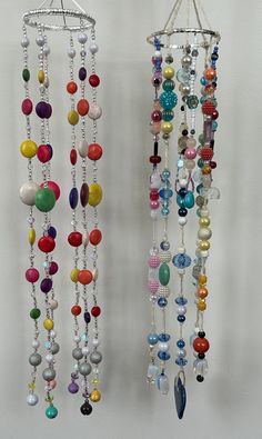 two wind chimes hanging on the side of a wall with beads attached to them