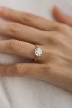 a woman's hand with a diamond ring on her left hand, resting on a white towel