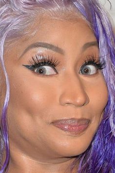 a close up of a person with purple hair and eyeliners on her face