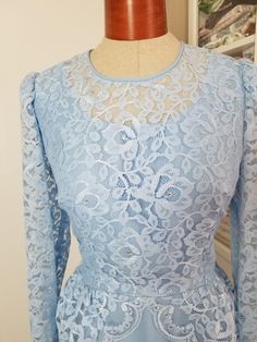 "Pretty dress in an icy periwinkle shade of blue. The top has a layer of lace in a peplum style that is longer in the back. The lace is adorned with tiny pearls and prong set rhinestones. This dress has long sleeves and zips up the back. Hook and eye at top of zipper. Has belt loops and no belt. Has some 40's vibes! Label reads, \"The Bridal Shoppe of Columbus Ohio\". Was probably a mother of the bride dress. This is in good condition, except for it needs a few stitched on the zipper (see photo) Blue Fitted Lace Patchwork Dress, Light Blue Fitted Lace Dress, Light Blue Lace Trim Dress For Party, Light Blue Lace Trim Party Dress, Light Blue Lace Dress With Lace Trim For Party, Vintage Blue Lace Dress, Peplum Styles, Mother Of The Bride Dress, Ice Queen