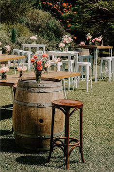 a wooden barrel sitting on top of a grass covered field next to tables and chairs