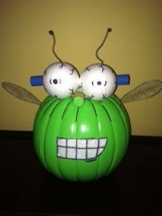 a green pumpkin with two googly eyes on it