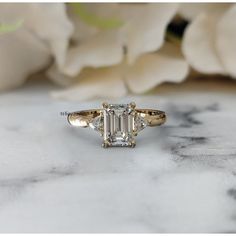 a diamond ring sitting on top of a table next to white flowers and a flower bouquet