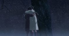 two people standing in the snow with their arms around each other