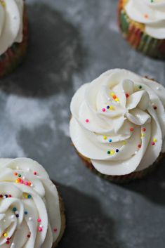 several cupcakes with white frosting and sprinkles