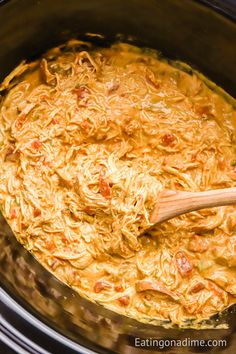 the food is being cooked in the crock pot with a wooden spoon on top