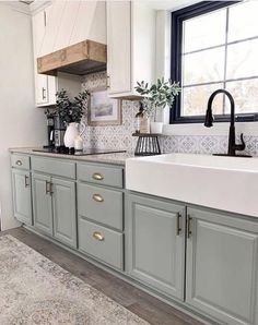 a kitchen with gray cabinets and white counter tops, black faucet above the sink