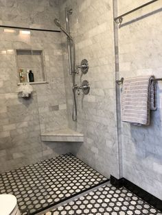 a bathroom with black and white tiles on the floor, shower head, and toilet