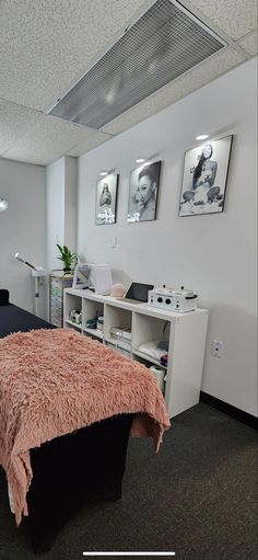 a bedroom with a bed, desk and pictures on the wall above it in an office